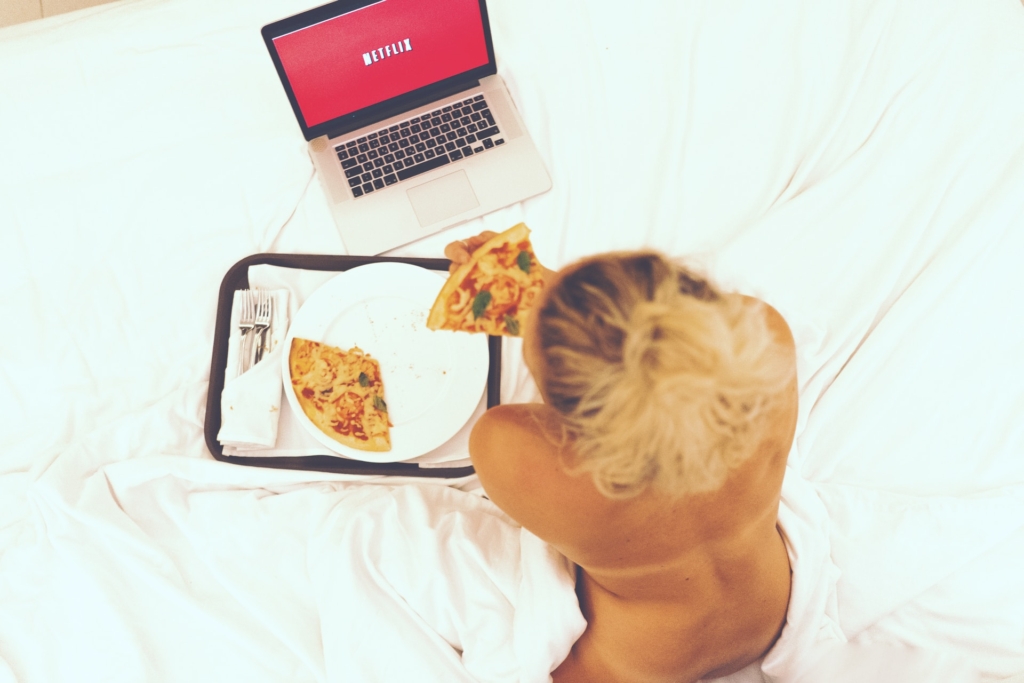 hosting y dominio explicado con pizzas, mujer comineod pizza con una laptopa lado de ella